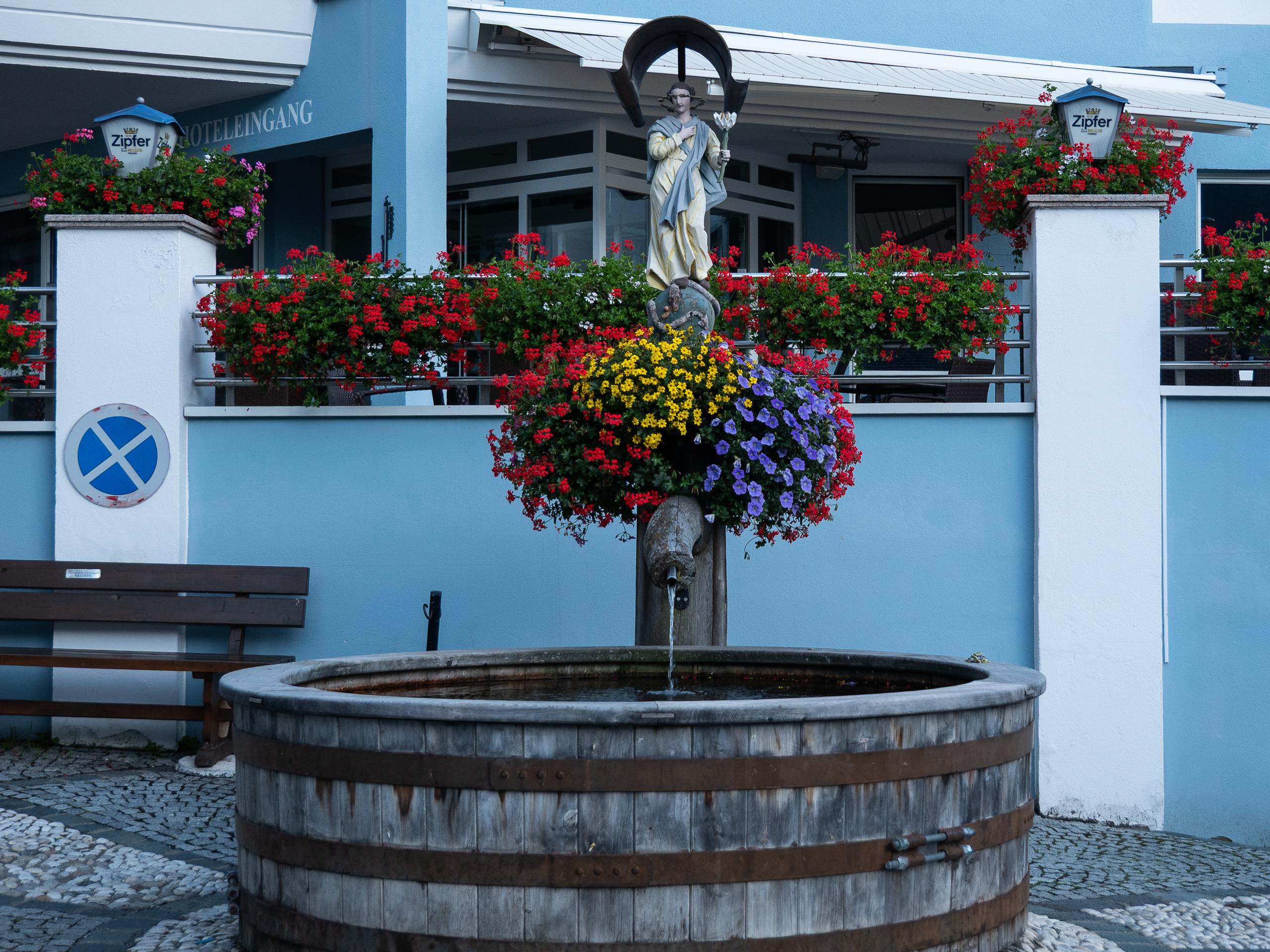 Dorfbrunnen mit Marienfigur und Blumenschmuck in Nauders
